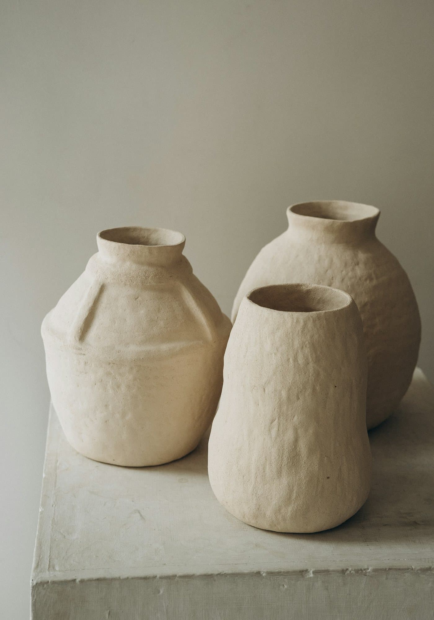 Three white ceramic jars on a white table