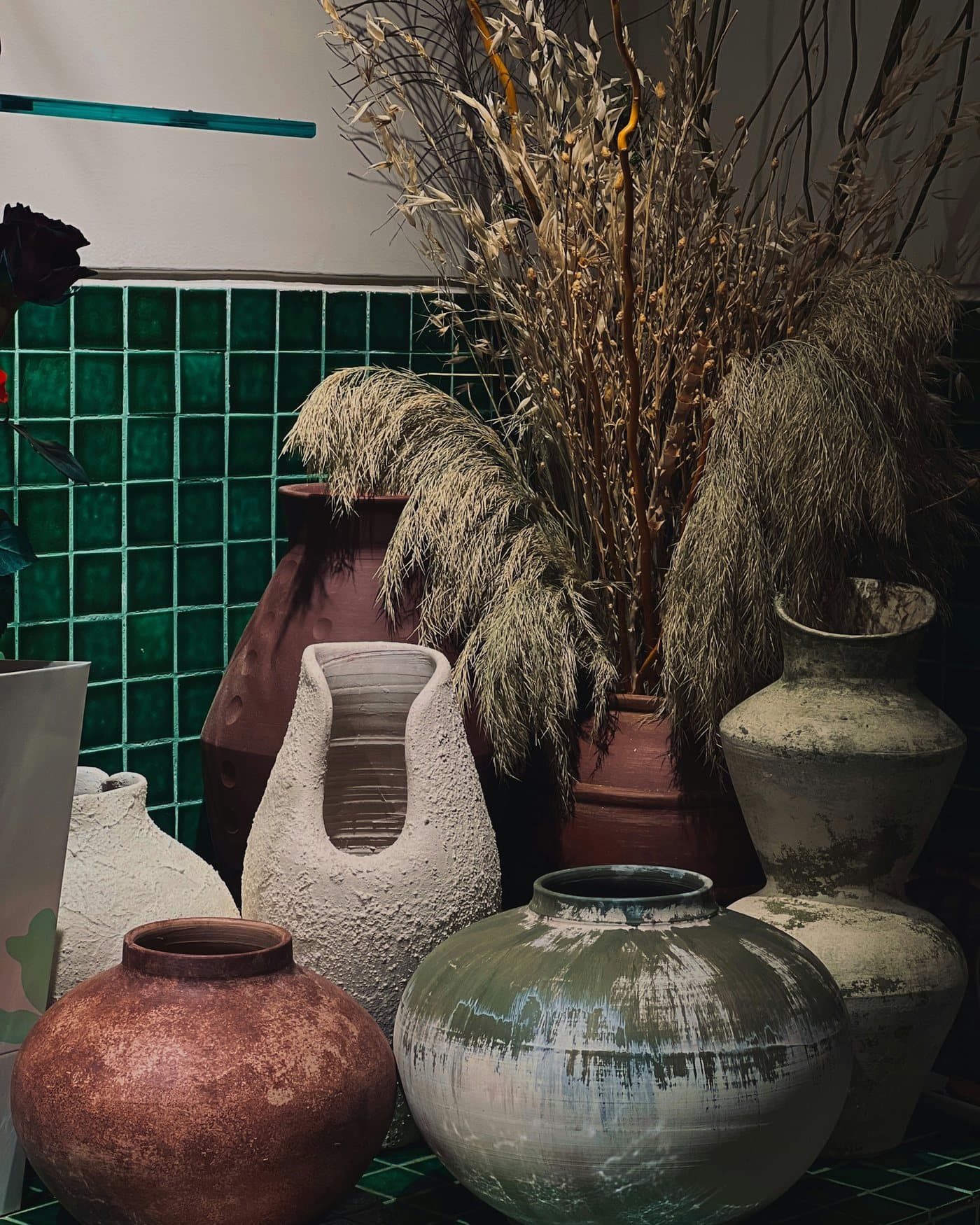 Dried grasses in ceramic vases on green tiles