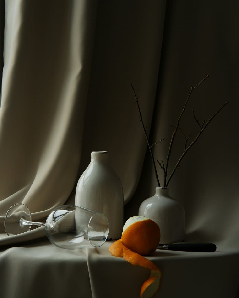 White vases and a glass on draped cloth